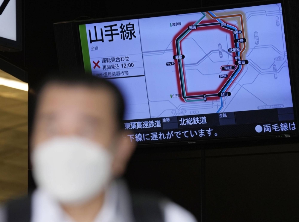 A commuter walks in front of a monitor displaying information on the halted JR Yamanote Line at Tokyo's Yurakucho Station on Monday morning.