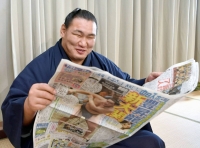 Hoshoryu looks at a newspaper during a news conference in Nagoya on Monday. | KYODO