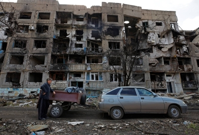 A local resident stands next to a car in front of a residential building heavily damaged in the course of the Russia-Ukraine war, in the settlement of Toshkivka, in the Luhansk province of Russian-controlled Ukraine on March 24.