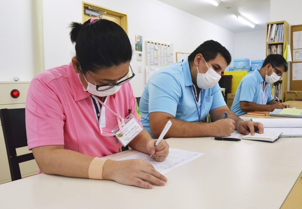 Foreign workers take notes during a meeting at a nursing care facility operator in Nagoya.