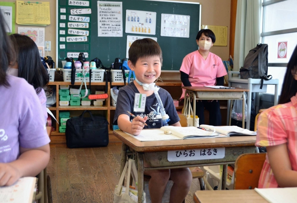 Haruki Hirao, second grader at Torikai Elementary School in Kurume, Fukuoka Prefecture, attends a mathematics class in May as nurse Yoshimi Yoshiyama looks on from the back of the classroom.