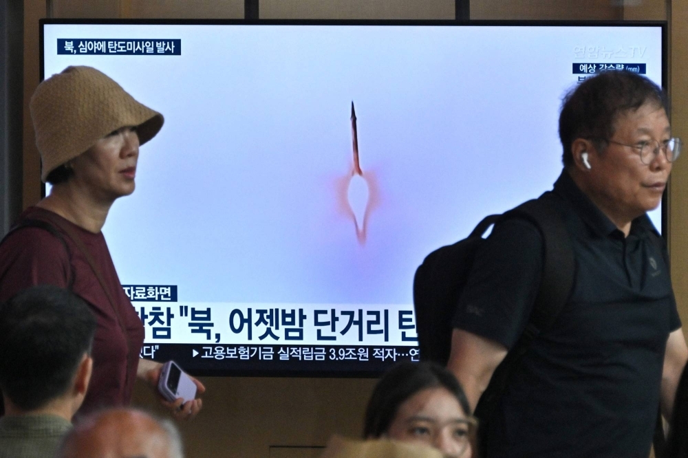 People walk past a television screen showing a news broadcast with file footage of a North Korean missile test at the main railway station in Seoul on Tuesday.