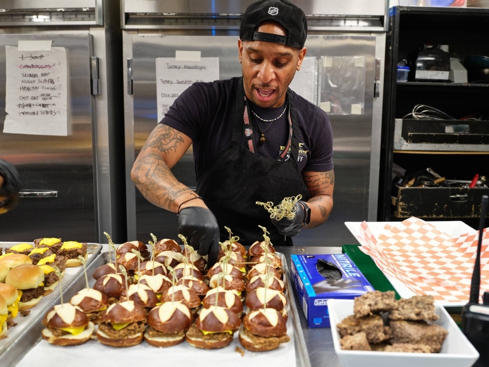 Jacob Curry puts some finishing touches on a sandwich spread at a Lizzo show.