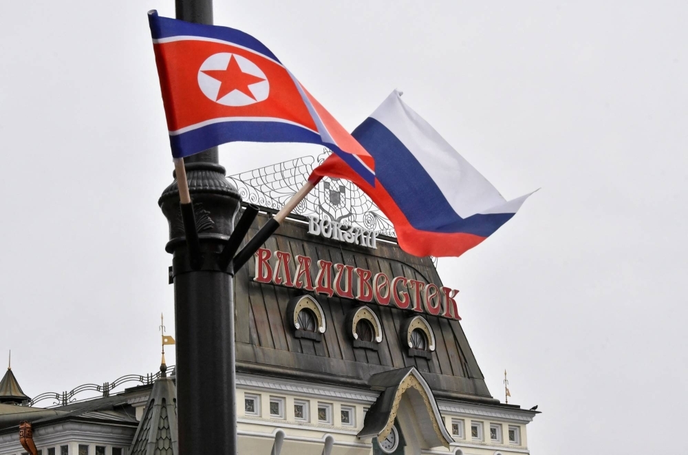 Russian and North Korean flags fly above a street in Vladivostok, Russia, in 2019. As Pyongyang prepares to mark the Korean War's 70th anniversary, Kim Jong Un's regime has Russia to thank.