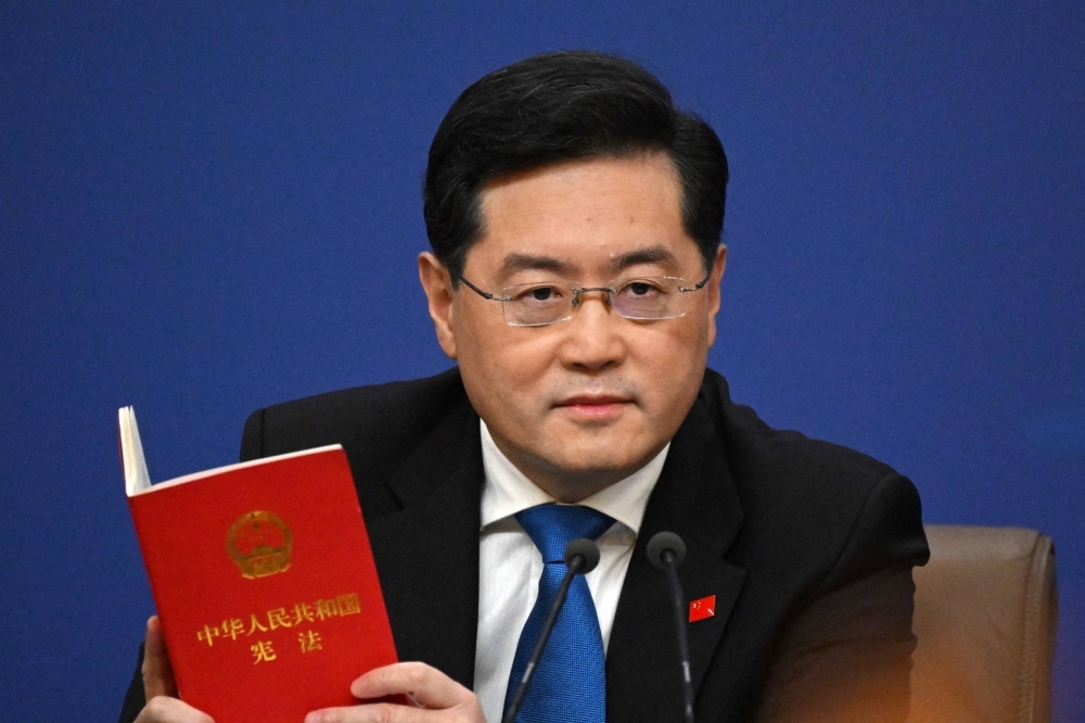 Then-Chinese Foreign Minister Qin Gang holds a copy of China's constitution during a news conference at the National People's Congress in Beijing in March.