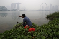A man catches a fish along the bank overlooking the Singapore skyline shrouded by haze in 2015.  | REUTERS