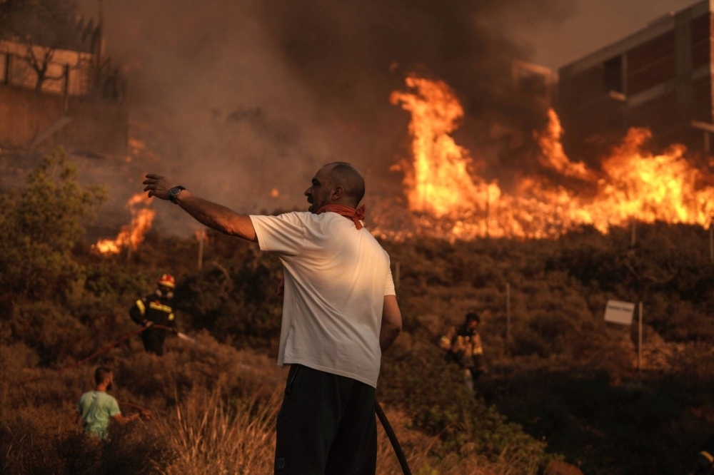 Firefighters and volunteers work to extinguish a burning field during a wildfire in Saronida, south of Athens, Greece, on July 17.
