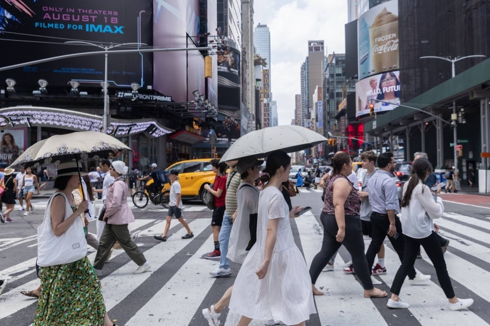 Pedestrians hold umbrellas for protection from the sun during a heat wave in New York on Thursday.