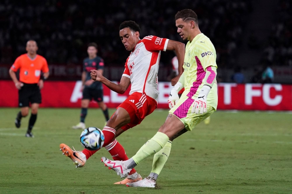 Bayern midfielder Jamal Musiala (left) fights for the ball against Manchester City goalkeeper Ederson during their friendly at Tokyo's National Stadium on  Wednesday.