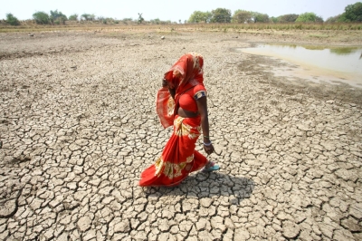 A woman walks on the bottom of a dried pond on a hot day in Mauharia, India, in May 2022. 