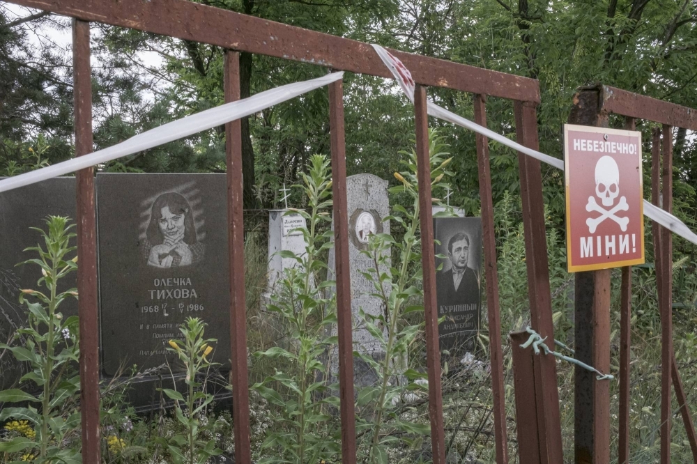 A sign warning for the presence of mines inside a cemetery in Sviatohirsk, Ukraine, in June