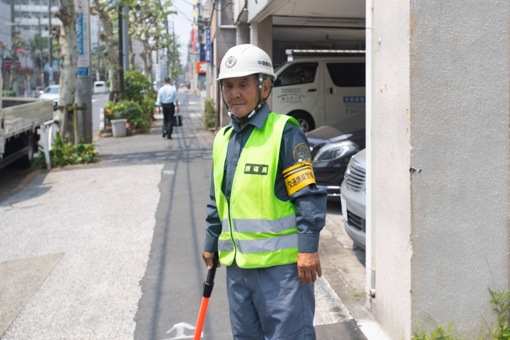 An 81-year-old traffic guard keeps watch at a construction site in Tokyo's Sumida Ward on July 19.