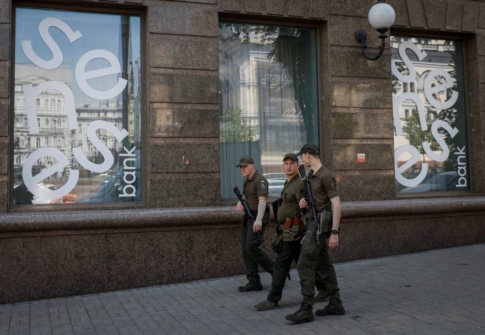 Military personnel patrol a street outside a branch of Ukraine's Sense Bank in central Kyiv in June.