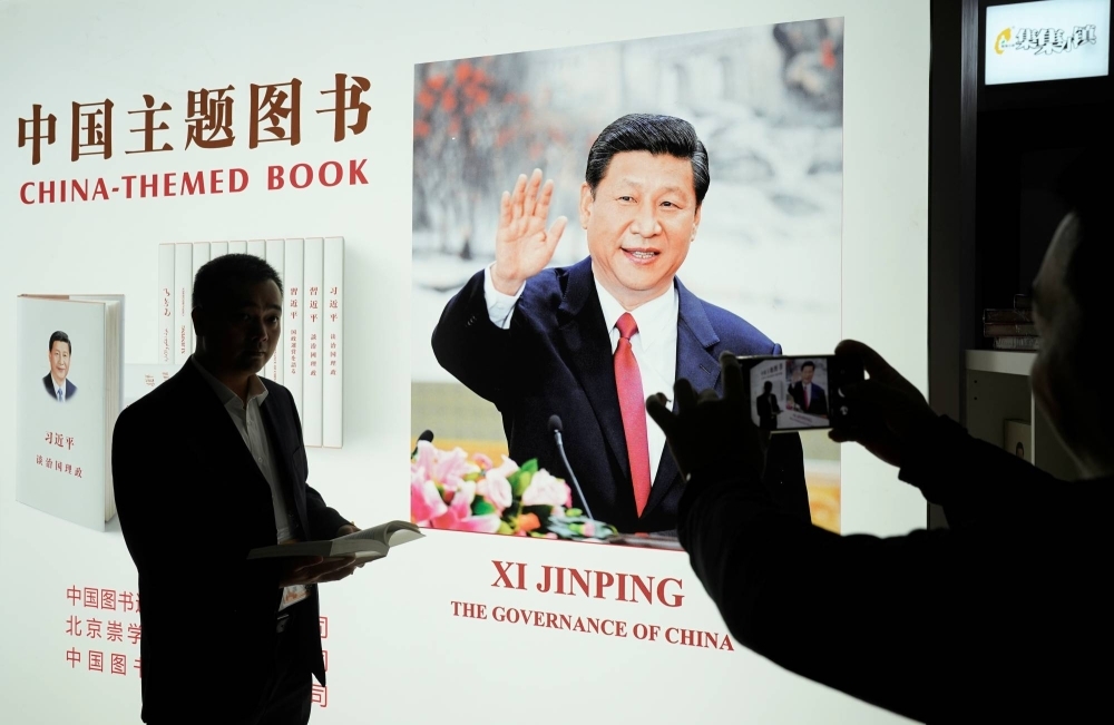 A man poses for pictures at a booth showing off a book by Chinese leader Xi Jinping during the China International Import Expo at the National Exhibition and Convention Center in Shanghai in November 2018. 