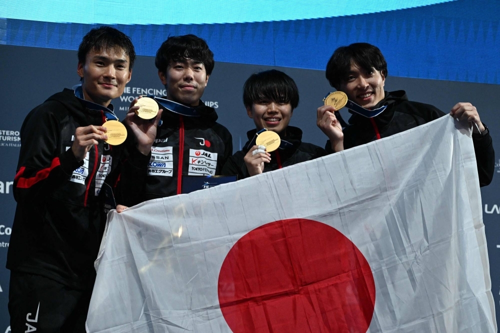 The Japanese team poses on the podium after winning gold in the men's team foil event at the Fencing World Championships in Paris on Sunday.