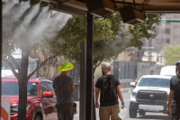 Residents walk through misters during a heat wave in Phoenix, Arizona, on July 20. | Bloomberg
