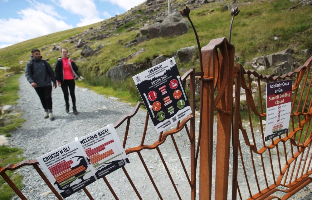 Signs hang on a gate as people hike in the Pen y Pass at the foot of Mount Snowdon near Llanberis, Wales, in 2020. For residents of deprived urban areas, going to natural green spaces can be prohibitively expensive.