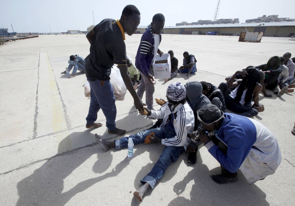 Migrants at a base near Tripoli hand out food to other migrants after they were detained by the Libyan navy in September 2015. 

