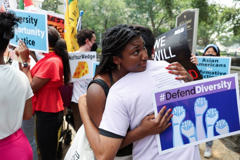 People embrace each other as demonstrators for and against the U.S. Supreme Court decision to strike down race-conscious student admissions programs at Harvard University and the University of North Carolina confront each other, in Washington on June 29.