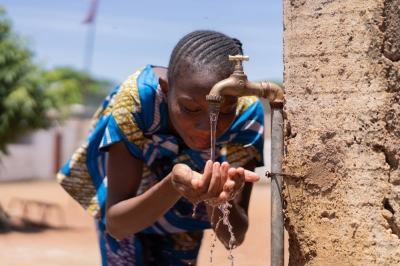A young girl drinks water from a faucet in Bamako. At a site just 55 kilometers from Mali's capital city, pure hydrogen gas seeps from the ground like crude oil or methane.