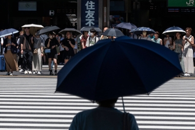 People use umbrellas and parasols to seek relief from soaring temperatures while waiting to cross a street outside Tokyo's Shinjuku Station last week.