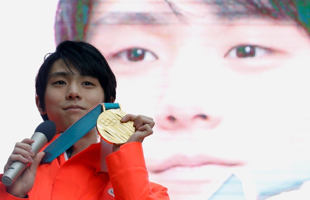 Figure skater Yuzuru Hanyu poses with his gold medal from the Pyeongchang 2018 Winter Olympics, during a fan event in Tokyo in February 2018.