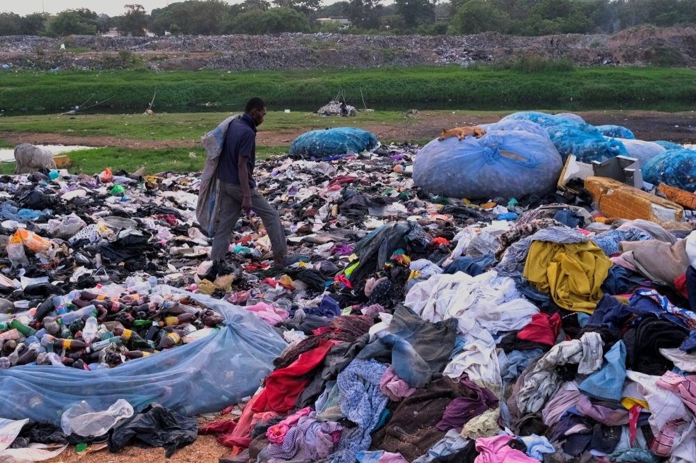 A man scavenges a dumpsite where secondhand clothes are discarded in Accra, Ghana, in December 2022.