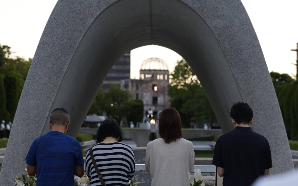 People pray in front of the cenotaph on Sunday, the 78th anniversary of the atomic bombing of Hiroshima, at the city's Peace Memorial Park as the Atomic Bomb Dome looms in the background.