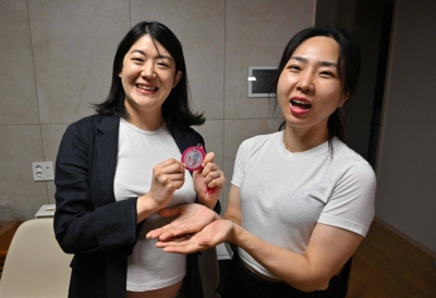 South Korean lesbian couple Kim Kyu-jin (left) and her wife, Kim Sae-yeon, pose with a "pregnant woman" badge during an interview in Seoul last month.