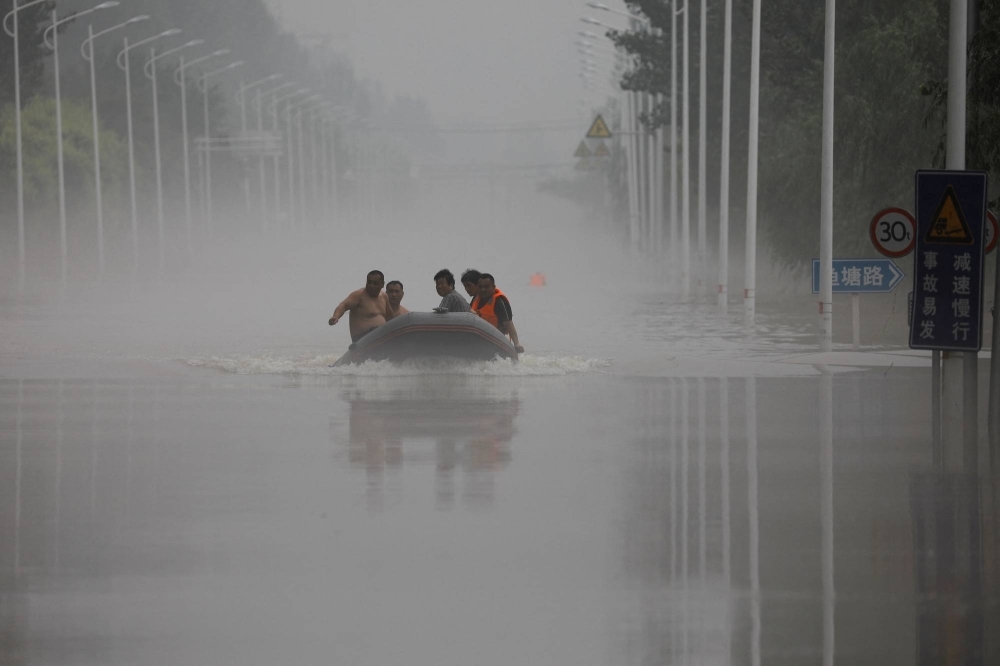 People ride a boat through a flooded road after Typhoon Doksuri in Zhuozhou, Hebei province, China, on Thursday.