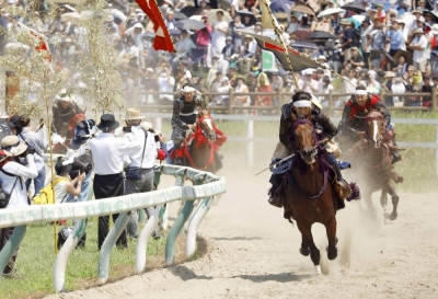 Riders dressed as samurai participate in an annual Soma Nomaoi festival in Minamisoma, Fukushima Prefecture, on July 30. Two horses died from heatstroke in the event.