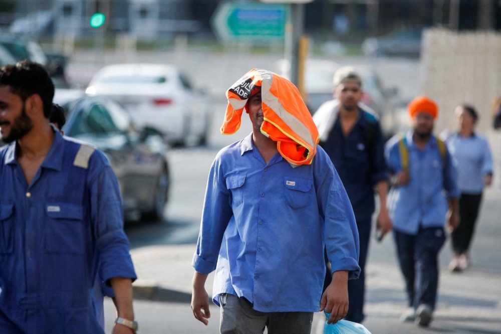 A laborer covers his head with his safety vest to shade himself from the sun during his afternoon break in Manama, Bahrain.