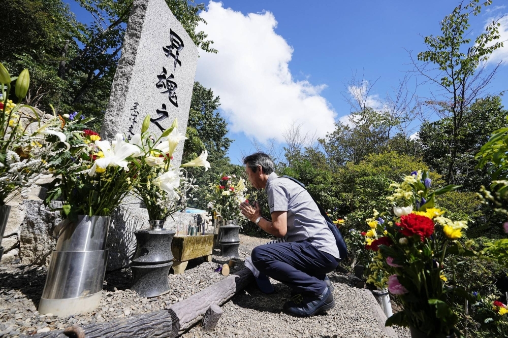 A man prays at a memorial for the victims of a deadly 1985 Japan Airlines crash in the village of Ueno, Gunma Prefecture, on Saturday.