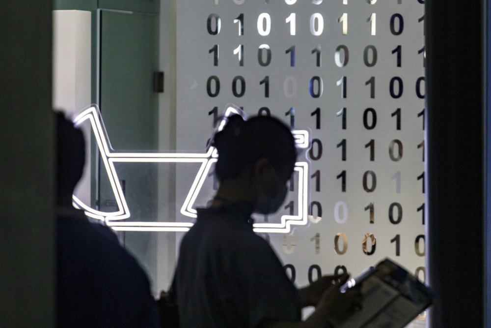 An attendee walks past a wall decorated with binary code during July's World Artificial Intelligence Conference (WAIC) in Shanghai.