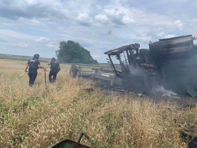 A harvesting combine burns after hitting an anti-tank mine in a wheat field near the village of Vilkhivka, in Ukraine's Kharkiv Region, in July 2022.  