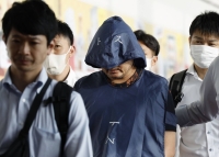Hiroki Ito (center), who was arrested Wednesday along with 55-year-old Shigeru Sato over their alleged involvement in a Cambodia-based fraud ring, arrives at Haneda Airport on Thursday, following their deportation from the Southeast Asian country. | KYODO