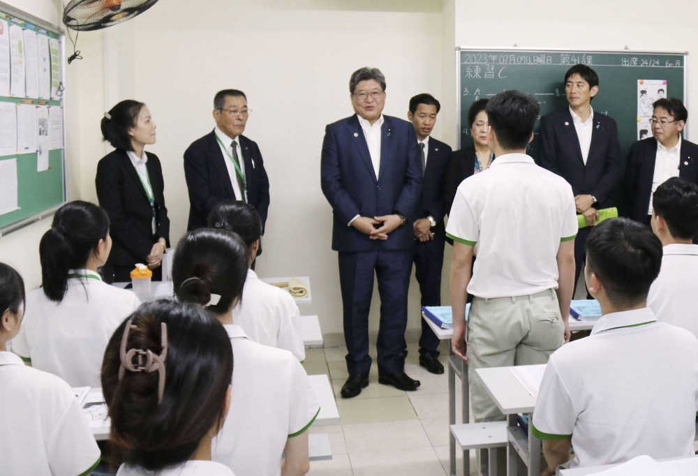 Koichi Hagiuda (center), the policy chief of the ruling Liberal Democratic Party, visits a dispatching agency for foreign trainees in Hanoi and talks to students there last month.