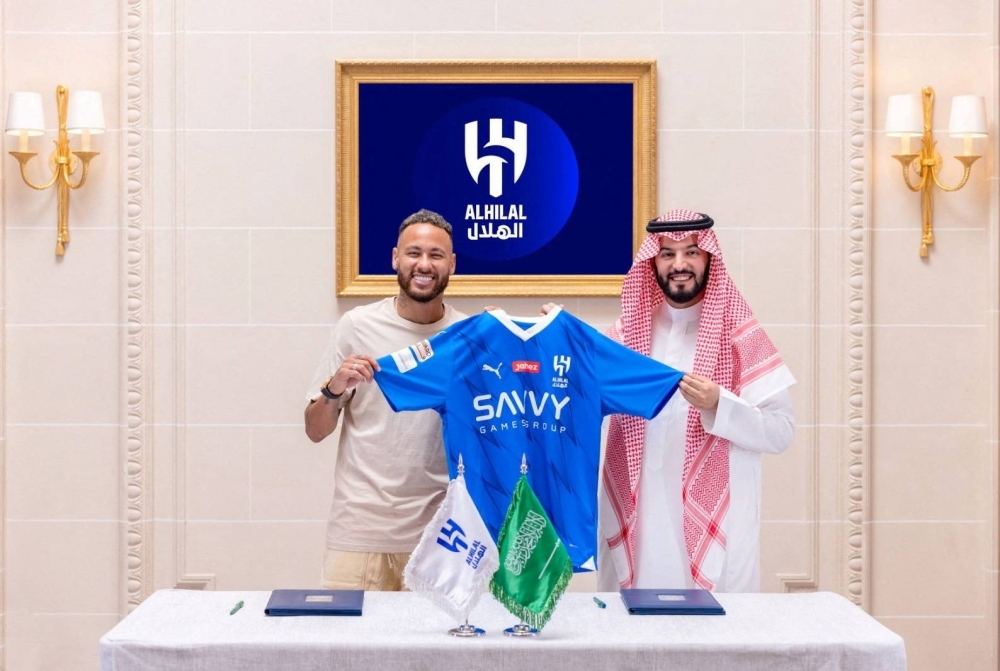 Al Hilal's new signing Neymar (left) holds the club's shirt as he poses with President Fahd bin Saad Al-Nafel during a signing event in Paris on Tuesday.