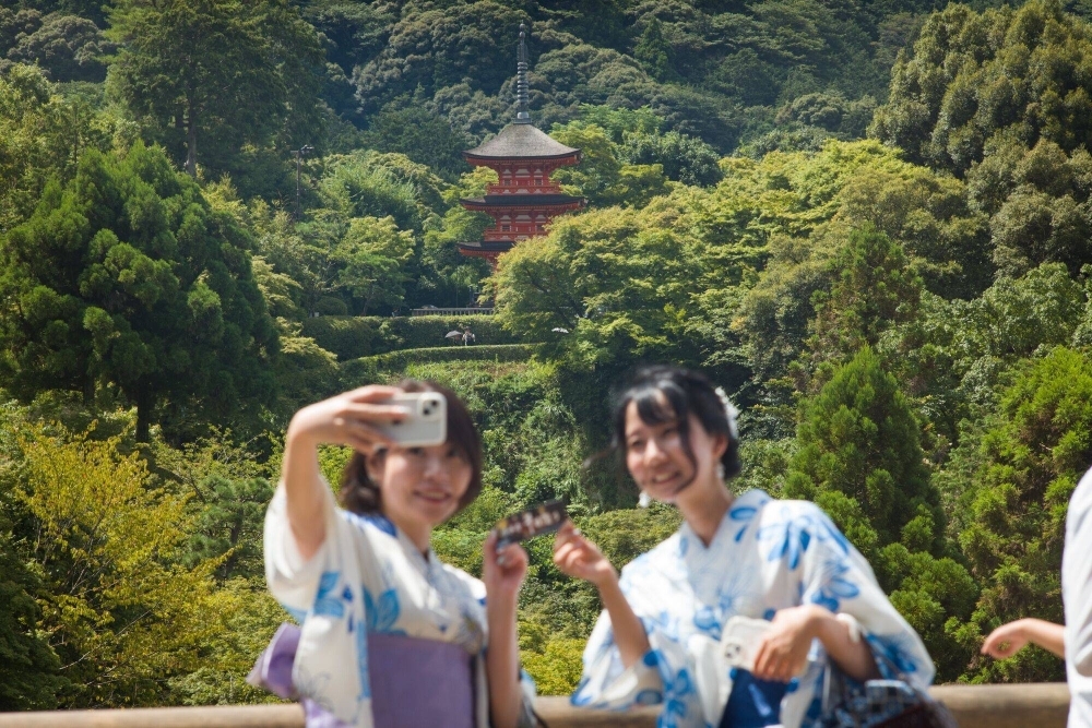 Kimono-clad visitors take selfie photographs at Kiyomizu Temple in Kyoto on Friday.