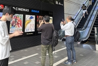 Fans in Tokyo take pictures of the poster for "The Boy and the Heron." | Anika Osaki Exum
