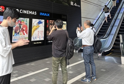 Fans in Tokyo take pictures of the poster for "The Boy and the Heron."