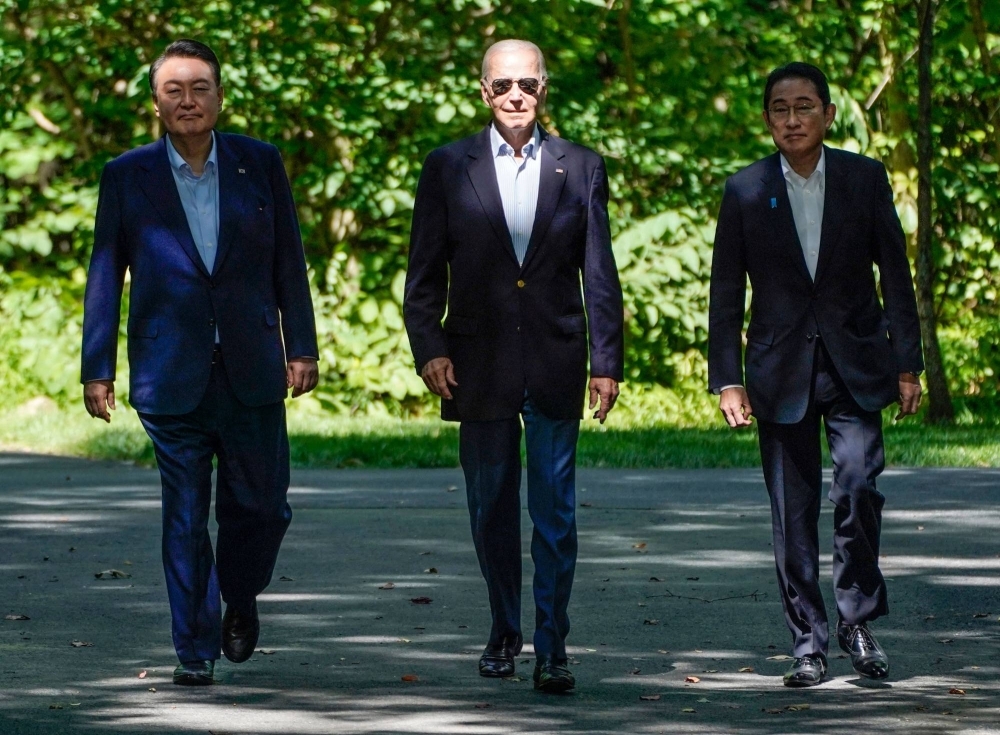 U.S. President Joe Biden walks with Prime Minister Fumio Kishida and South Korean leader Yoon Suk-yeol as the three arrive for a joint news conference during a trilateral summit at Camp David, near Thurmont, Maryland, on Friday.