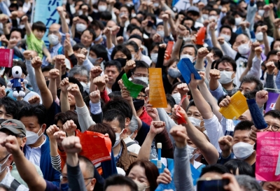 Members of the Japanese Trade Union Confederation, commonly known as Rengo, raise their fists as they cheer during their annual May Day rally to demand higher pay and better working conditions, in Tokyo, in  April.
