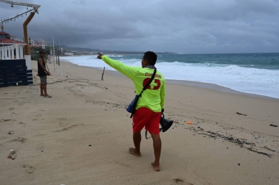 A lifeguard asks a young man to leave the beach in Los Cabos in Mexico's Baja California state as Hurricane Hilary brings heavy rains to the area. 