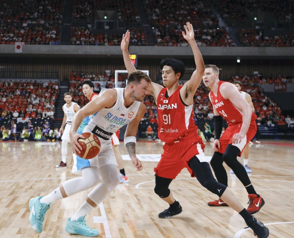 Japan's Hirotaka Yoshii (center) defends against Slovenia's Luka Doncic during the first quarter at Tokyo's Ariake Arena on Saturday.