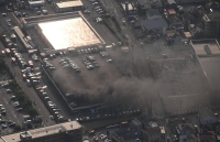 Smoke rises from a pachinko parlor parking lot in Atsugi, Kanagawa Prefecture, on Sunday. | Kyodo