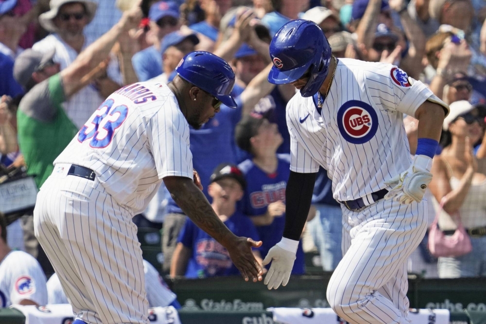 Seiya Suzuki (right) celebrates with the Cubs' third base coach after hitting his 12th homer of the season during a win over the Royals on Sunday.
