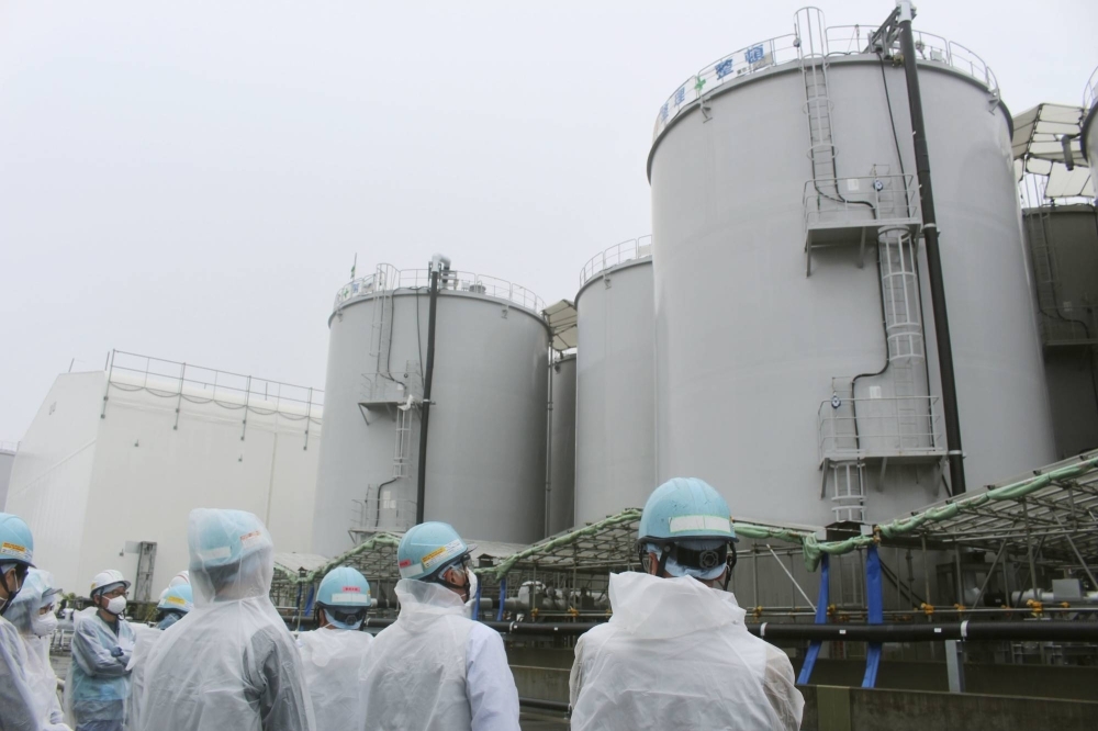 Members of the International Atomic Energy Agency inspect treated water tanks at the Fukushima No. 1 plant in June.
