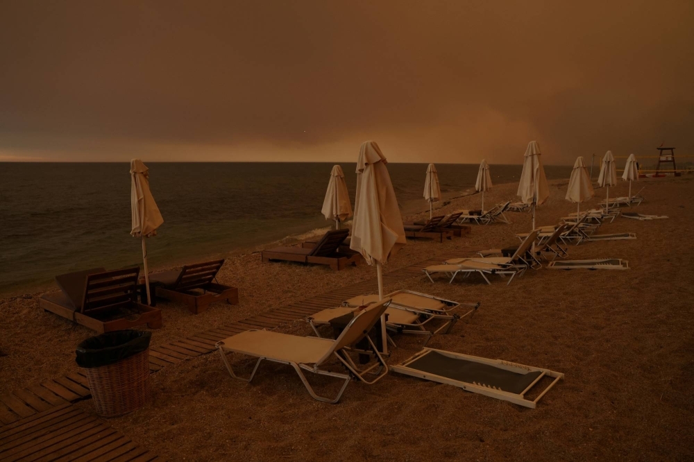 Smoke rises next to sunbeams and umbrellas as a wildfire burns at the beach of the village of Dikella, near Alexandroupolis, in the region of Evros, Greece, on Tuesday.