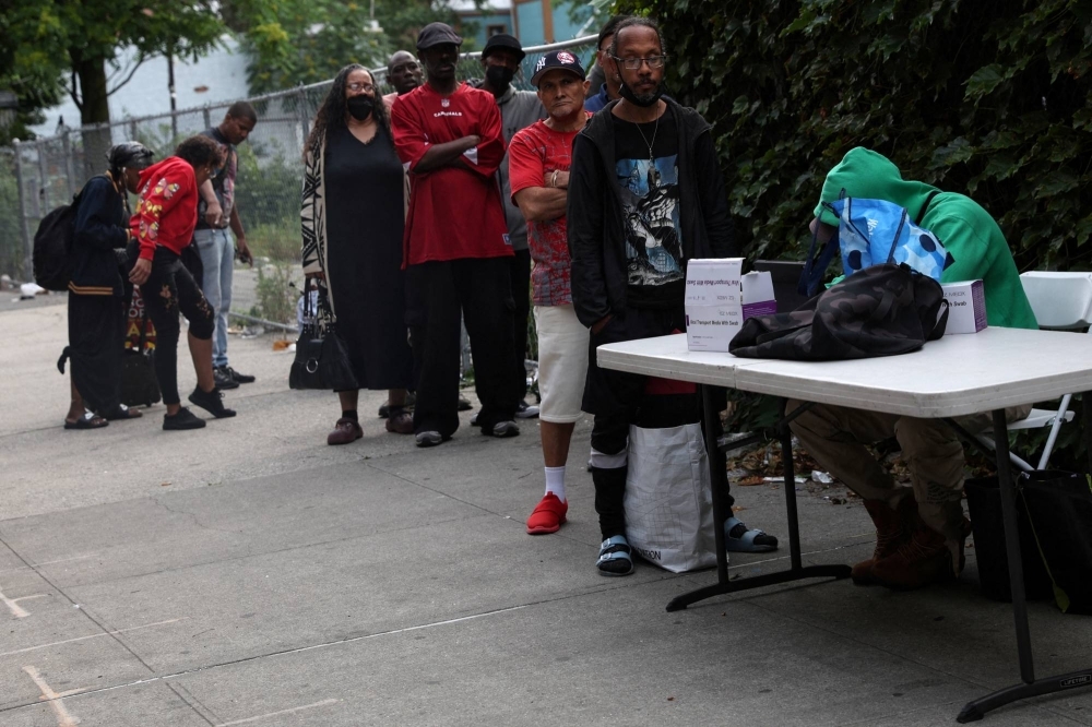 People wait in line to take a COVID-19 oral swab test on a sidewalk in the Harlem neighborhood of New York City on June 20.